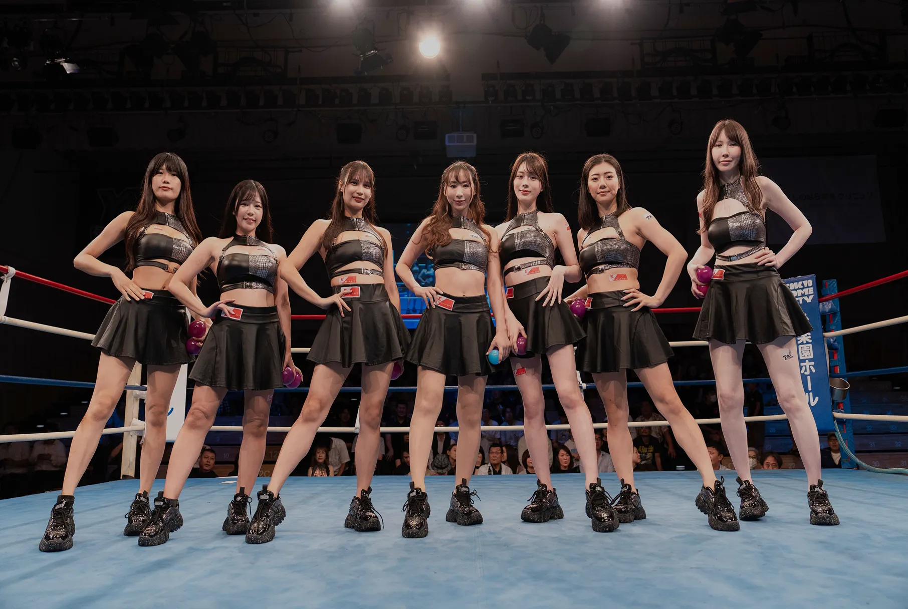 イーチケラウンドガールがボクシングのリング上で、黒の衣装を着てポーズをとっている