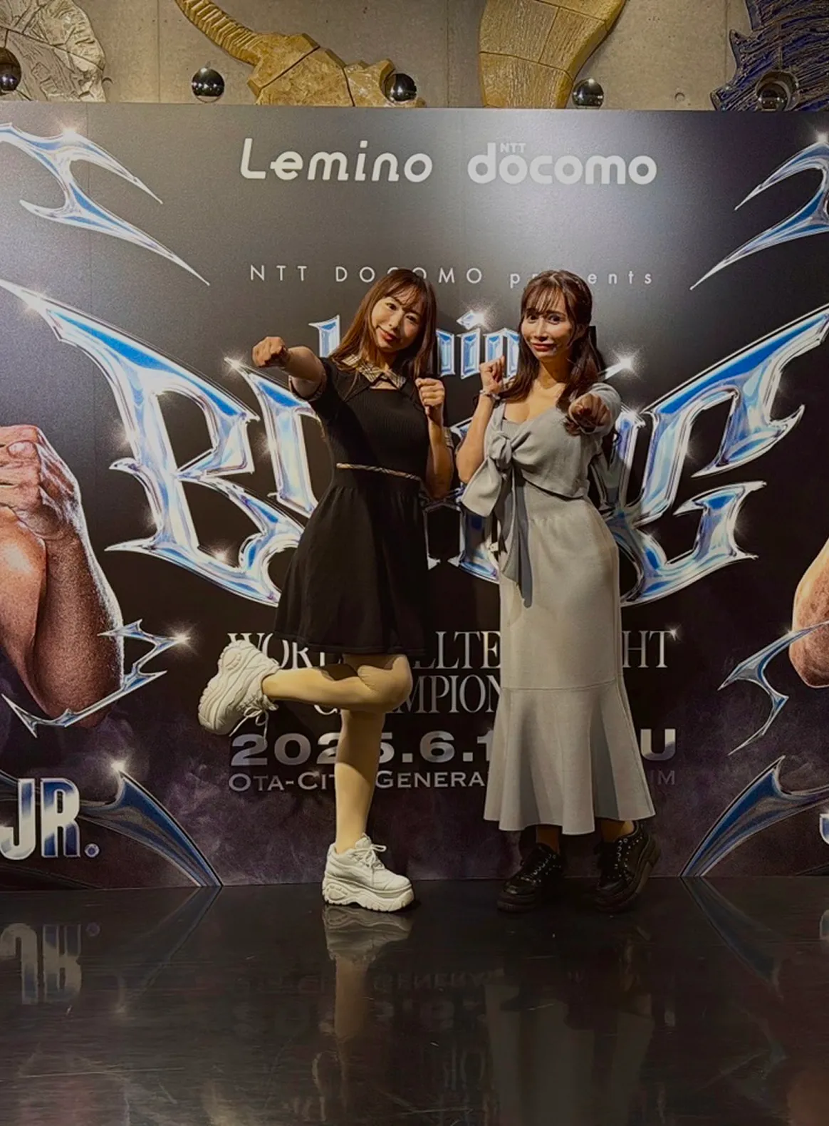 イーチケラウンドガールがボクシングの大パネル前でポーズをとっている