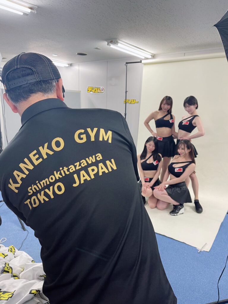 KANEKO GYMのTシャツを着たカメラマンに写真を撮られるイーチケラウンドガール